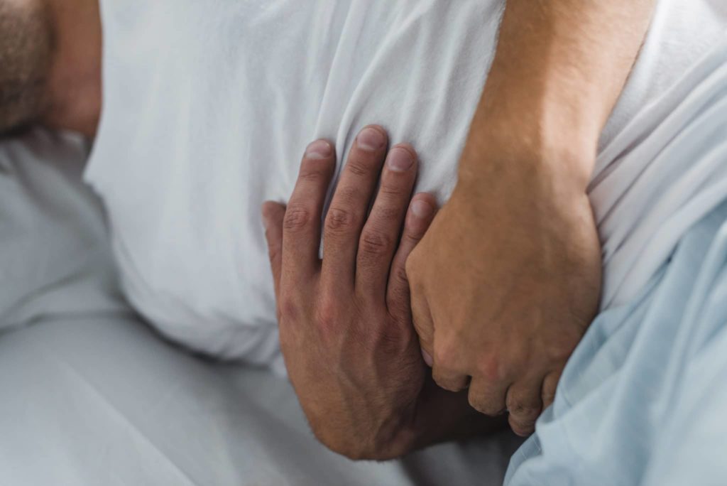 close-up partial view of man suffering from stomach pain in bed